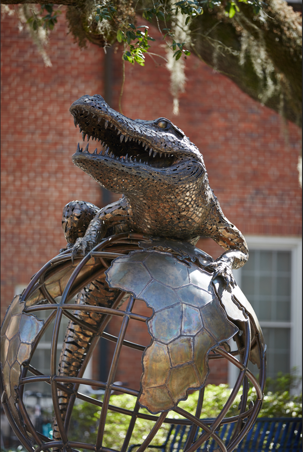 A statue of an alligator sitting on top of a globe.
